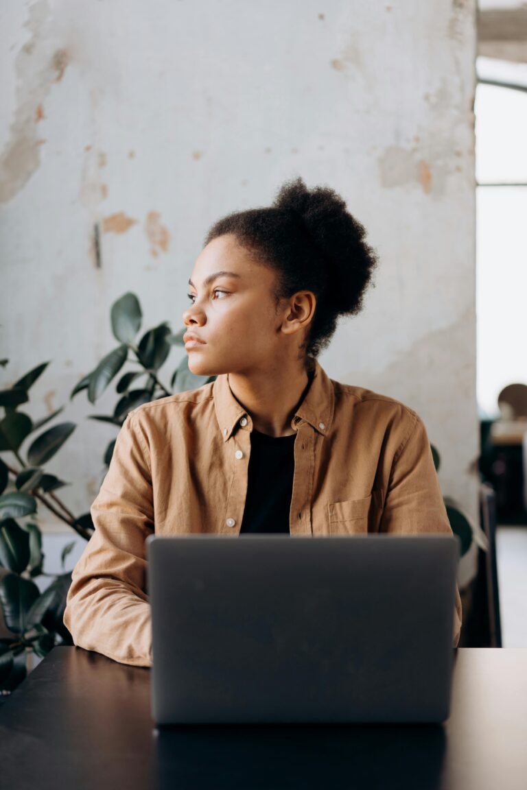 African American woman working on a laptop in a stylish, light-filled office space.